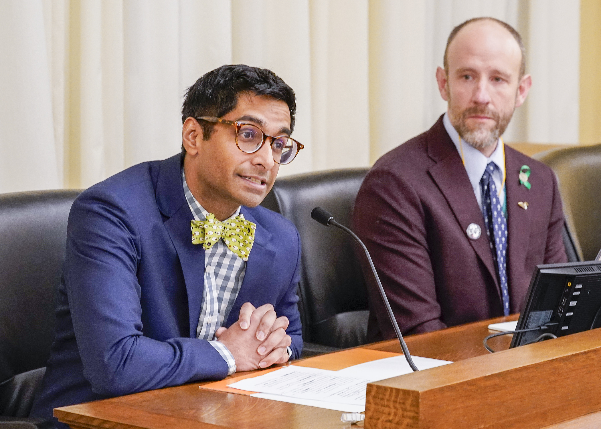 Dr. Krishnan Subrahmanian, chief medical officer for Hennepin Health, testifies Feb. 19 during commerce committee discussion of a bill sponsored by Rep. Alex Falconer, right. (Photo by Andrew VonBank)
